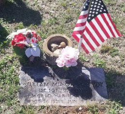 A veteran grave marker with an American flag and flowers