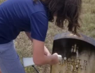 A young volunteer cleaning a veteran headstone