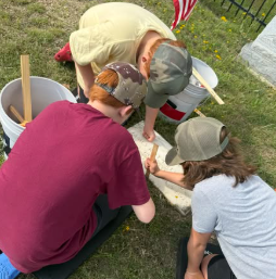 Volunteers working together to clean a cemetery marker