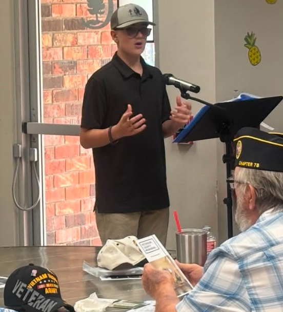 A young speaker addressing an audience at a microphone